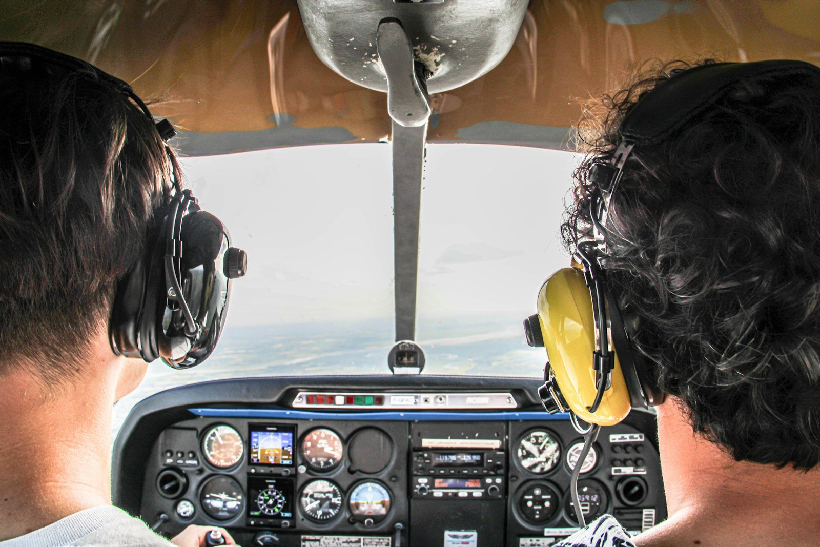 Two people in airplane cockpit flying over clouds